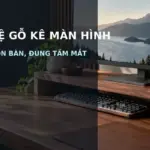 Kệ gỗ kê màn hình trong góc làm việc gọn gàng, bàn phím đặt bên dưới